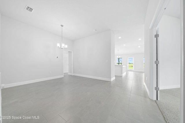 spare room featuring light tile patterned floors and a notable chandelier