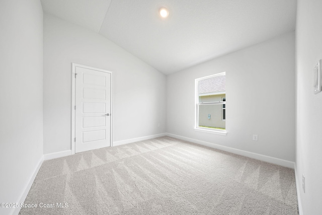 empty room featuring light colored carpet and vaulted ceiling