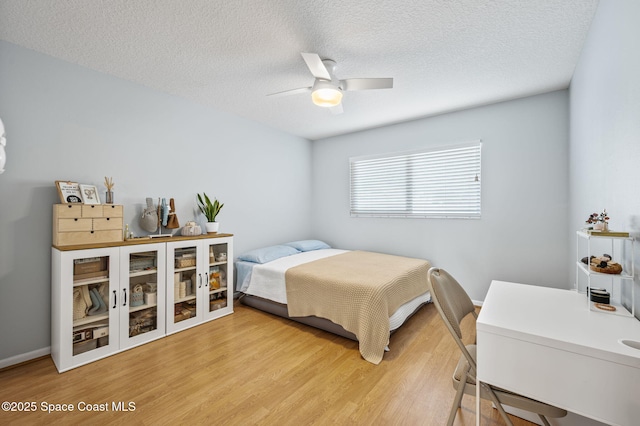 bedroom featuring hardwood / wood-style flooring, ceiling fan, and a textured ceiling