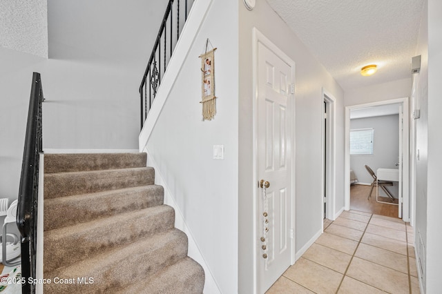 stairs with tile patterned floors and a textured ceiling