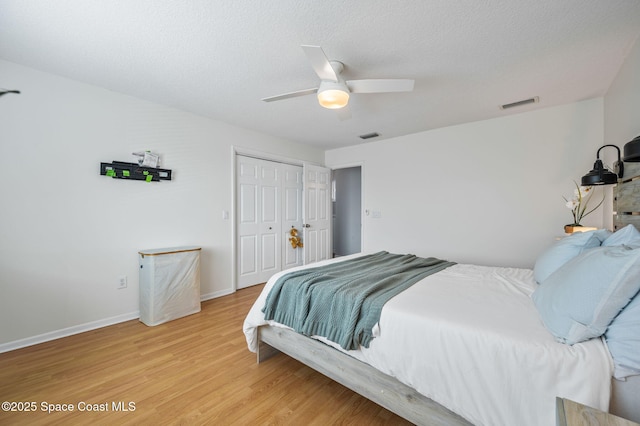 bedroom with hardwood / wood-style floors, a textured ceiling, a closet, and ceiling fan