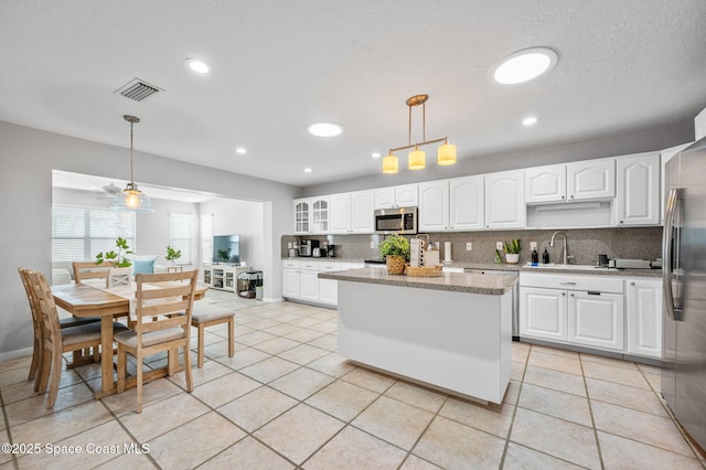 kitchen featuring sink, white cabinetry, light stone counters, pendant lighting, and stainless steel appliances