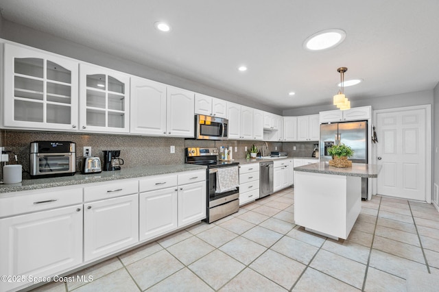 kitchen featuring light tile patterned flooring, appliances with stainless steel finishes, decorative light fixtures, white cabinetry, and decorative backsplash