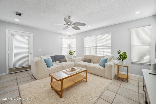 tiled living room with ceiling fan and a textured ceiling