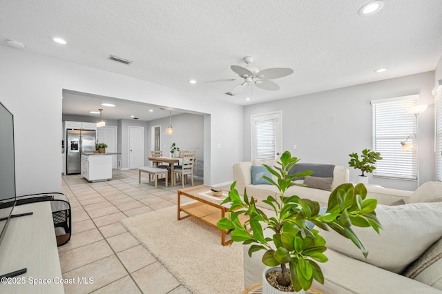 living room featuring ceiling fan, a textured ceiling, and light tile patterned floors