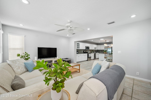 living room featuring ceiling fan, a textured ceiling, and light tile patterned floors