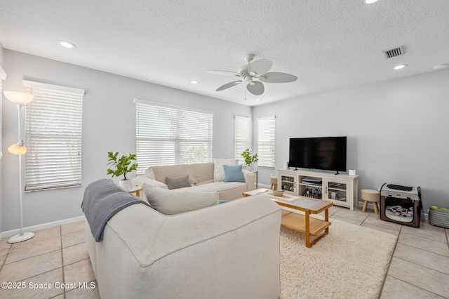 tiled living room featuring ceiling fan and a textured ceiling