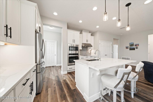 kitchen featuring hanging light fixtures, appliances with stainless steel finishes, sink, white cabinetry, and a kitchen island with sink