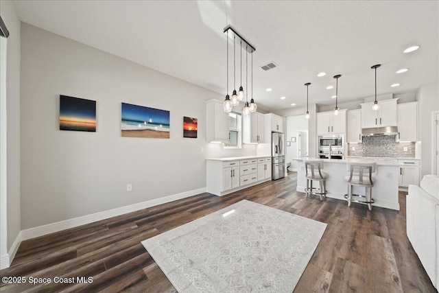 kitchen featuring pendant lighting, white cabinets, a center island, stainless steel appliances, and a kitchen breakfast bar