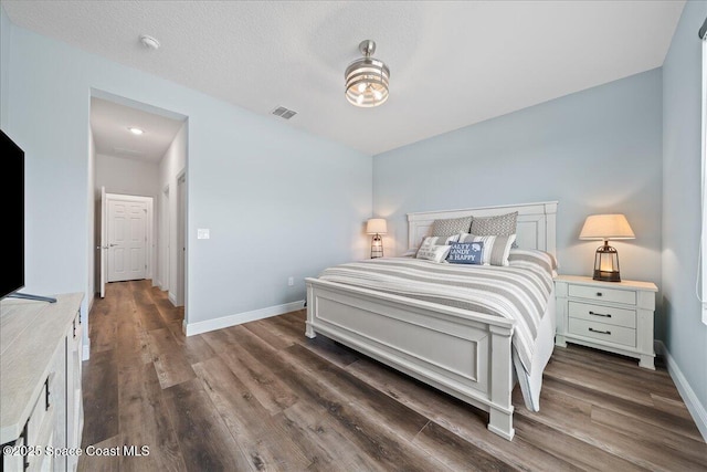 bedroom with a textured ceiling and dark hardwood / wood-style floors