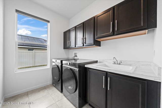 laundry room with cabinets, light tile patterned floors, sink, and washing machine and clothes dryer