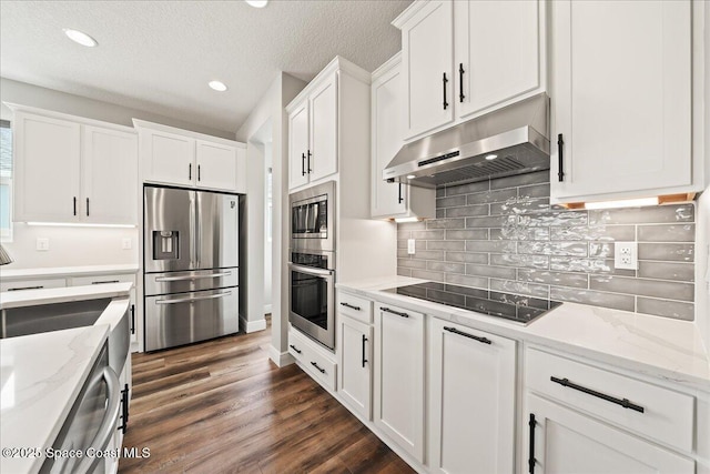 kitchen with stainless steel appliances, white cabinetry, light stone countertops, and dark hardwood / wood-style flooring