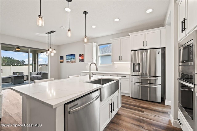 kitchen featuring white cabinets, hanging light fixtures, appliances with stainless steel finishes, and sink