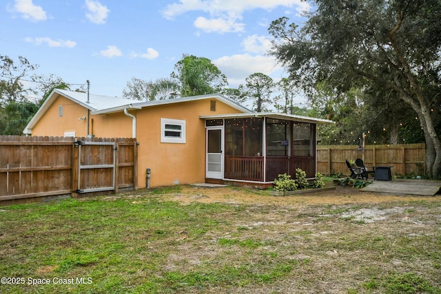 back of property with a sunroom and a lawn