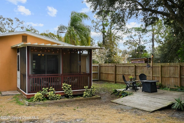 view of yard featuring an outdoor fire pit, a deck, and a sunroom