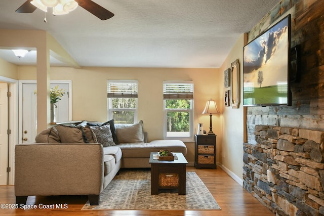 living room with hardwood / wood-style flooring, ceiling fan, and a textured ceiling