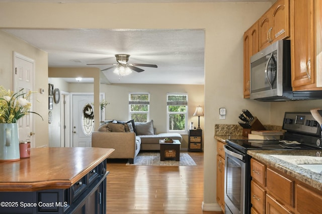 kitchen featuring ceiling fan, stainless steel appliances, and light hardwood / wood-style floors