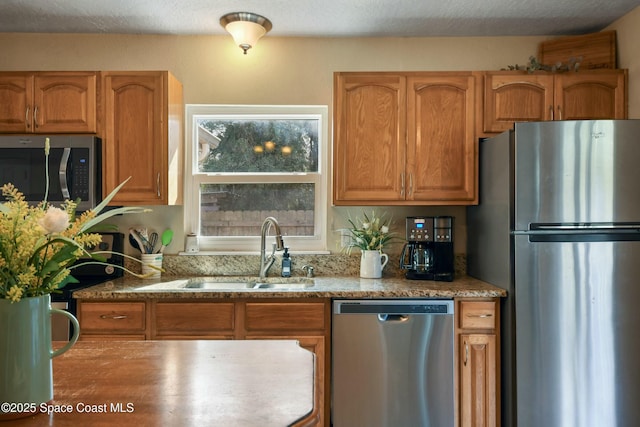 kitchen with appliances with stainless steel finishes, sink, and a textured ceiling