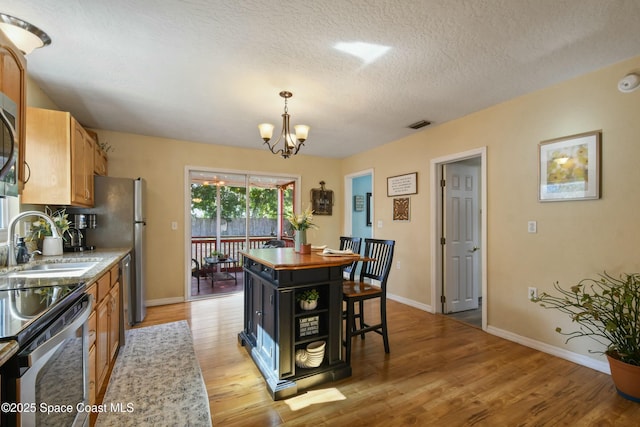 kitchen featuring pendant lighting, sink, a notable chandelier, a kitchen island, and light wood-type flooring