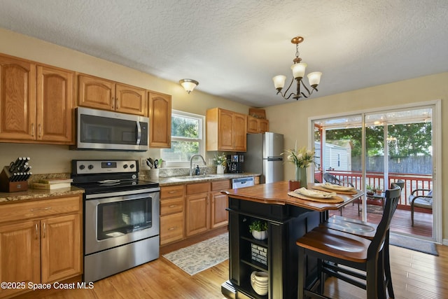 kitchen with sink, a chandelier, light hardwood / wood-style flooring, a textured ceiling, and stainless steel appliances