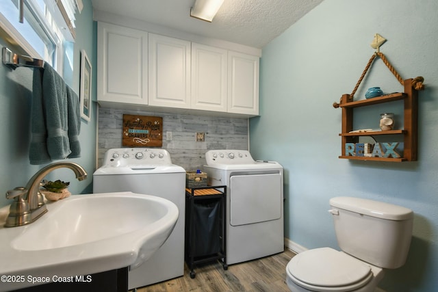 washroom featuring sink, washer and dryer, a textured ceiling, and light wood-type flooring