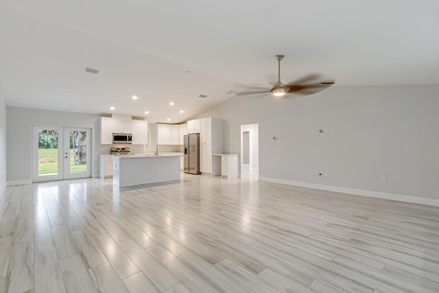 unfurnished living room featuring sink, vaulted ceiling, ceiling fan, and light hardwood / wood-style floors