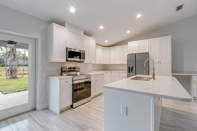 kitchen featuring white cabinets, appliances with stainless steel finishes, lofted ceiling, sink, and a kitchen island with sink