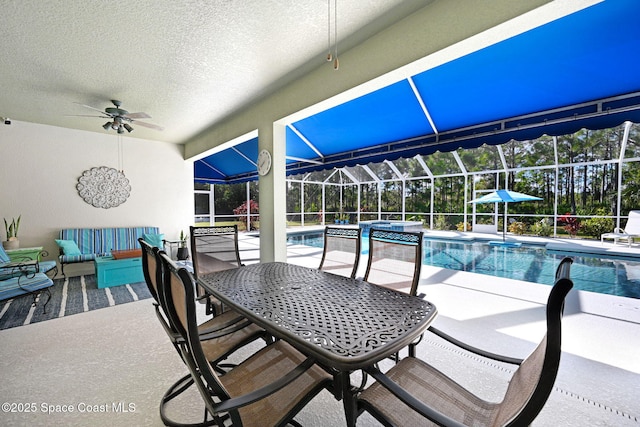 view of pool with ceiling fan, glass enclosure, and a patio area