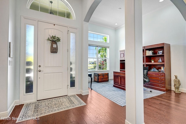 entrance foyer featuring a high ceiling, crown molding, and dark wood-type flooring