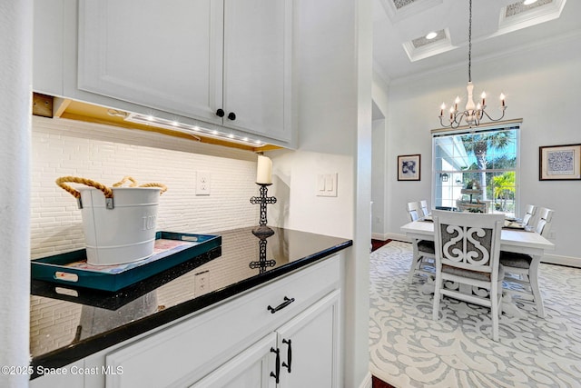 kitchen with pendant lighting, white cabinetry, a chandelier, decorative backsplash, and crown molding