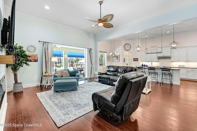 living room with dark hardwood / wood-style floors, a high ceiling, ornamental molding, a textured ceiling, and ceiling fan with notable chandelier