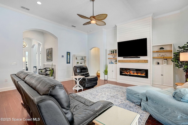 living room featuring hardwood / wood-style flooring, ceiling fan, ornamental molding, and a fireplace