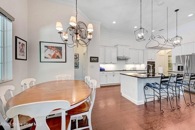 dining area featuring crown molding, dark hardwood / wood-style flooring, sink, and a notable chandelier