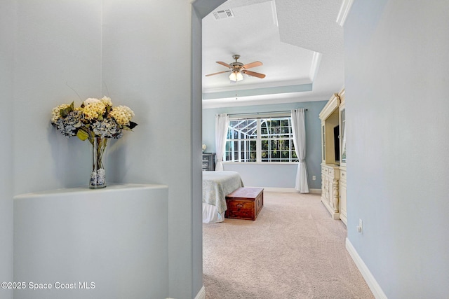 carpeted bedroom with ornamental molding, a textured ceiling, and a tray ceiling