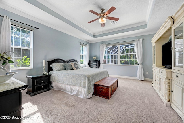 bedroom featuring light carpet, a textured ceiling, ornamental molding, a tray ceiling, and ceiling fan