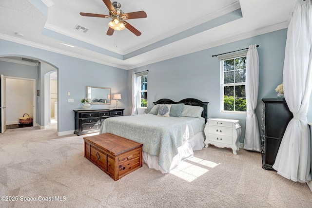 bedroom with crown molding, light colored carpet, a raised ceiling, and ceiling fan