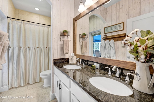 bathroom featuring wooden walls, tile patterned flooring, vanity, walk in shower, and toilet