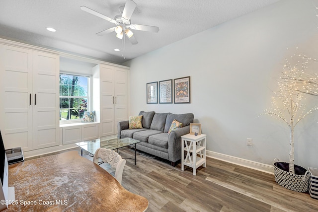 living room featuring ceiling fan, hardwood / wood-style flooring, and a textured ceiling