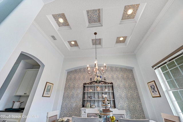 dining room with coffered ceiling, ornamental molding, a high ceiling, and an inviting chandelier