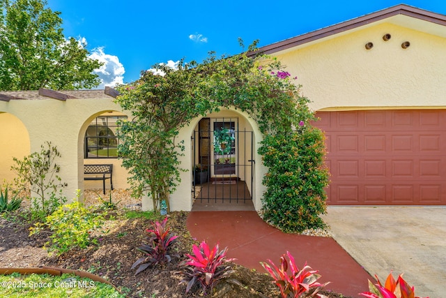 entrance to property with a garage and stucco siding