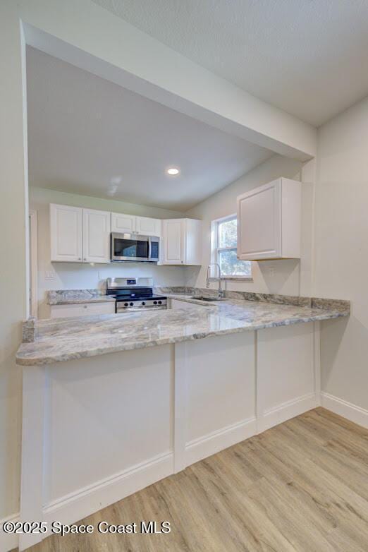 kitchen featuring stainless steel appliances, white cabinetry, light stone countertops, and sink