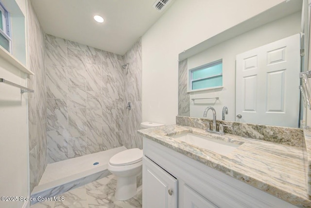 bathroom featuring tiled shower, vanity, and toilet