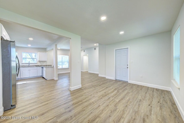 unfurnished living room featuring sink and light hardwood / wood-style floors