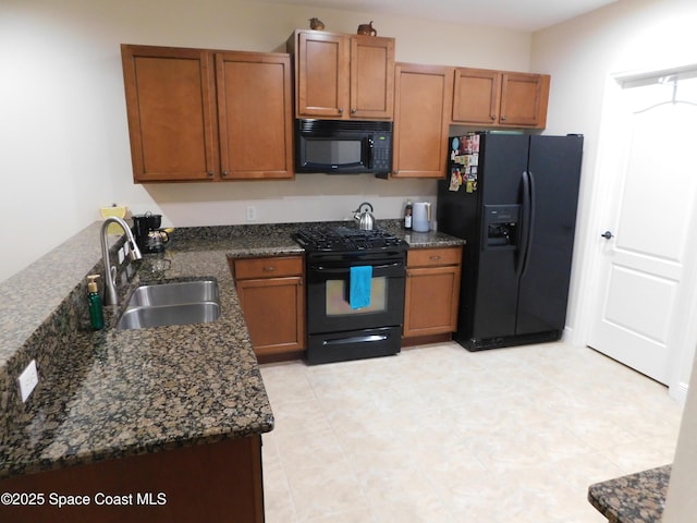 kitchen featuring sink, dark stone counters, and black appliances