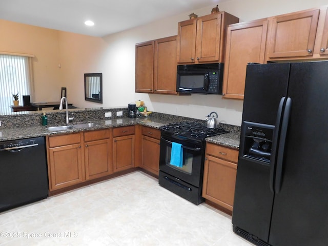 kitchen with sink, dark stone counters, and black appliances