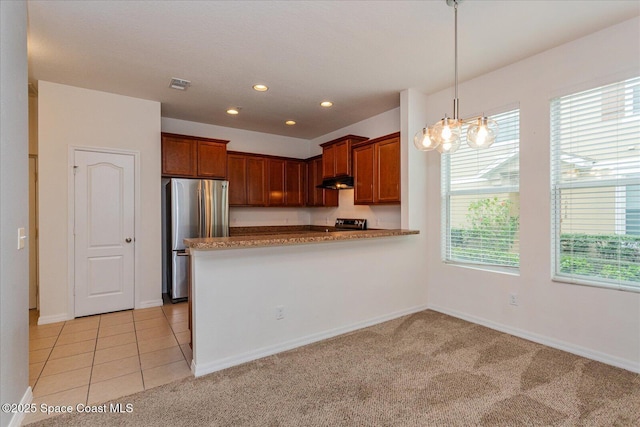 kitchen with a wealth of natural light, light tile patterned floors, kitchen peninsula, and stainless steel refrigerator