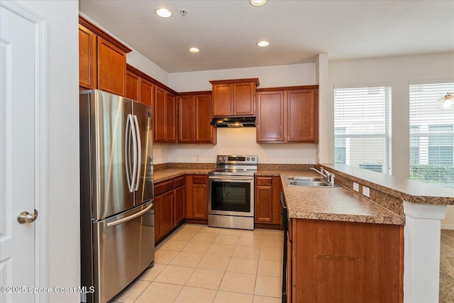 kitchen with appliances with stainless steel finishes, sink, kitchen peninsula, light tile patterned flooring, and a breakfast bar area