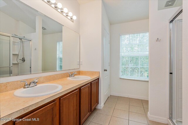 bathroom with walk in shower, vanity, and tile patterned flooring