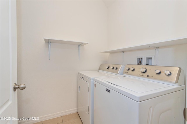 clothes washing area featuring washer and clothes dryer and light tile patterned floors