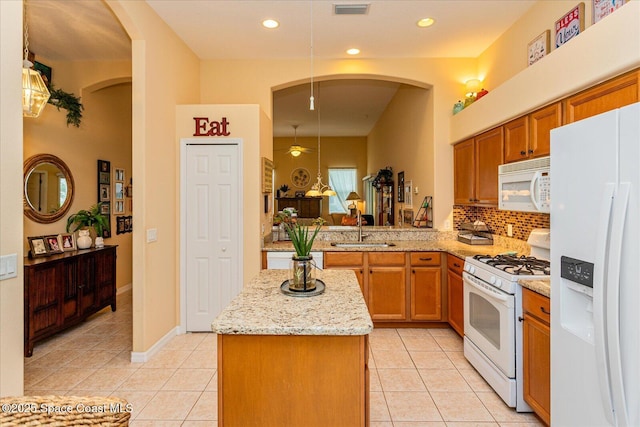 kitchen featuring white appliances, light tile patterned floors, sink, a kitchen island, and kitchen peninsula